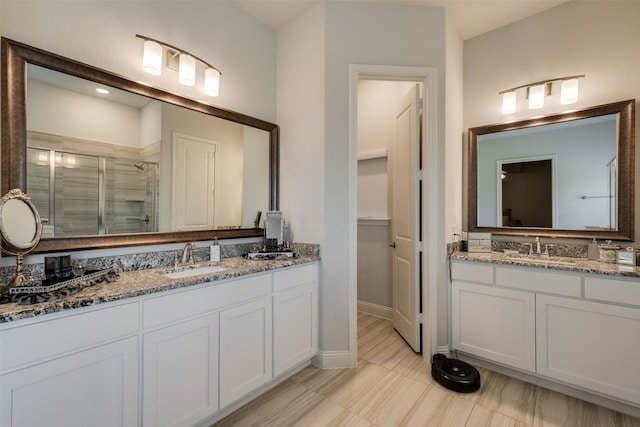 bathroom with baseboards, two vanities, a sink, and a shower stall