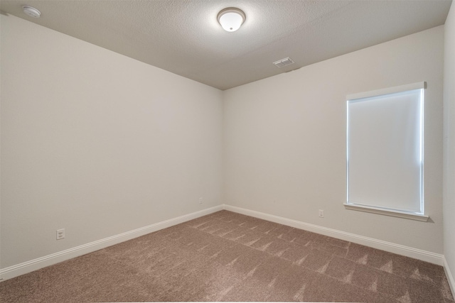 carpeted empty room with a textured ceiling, visible vents, and baseboards