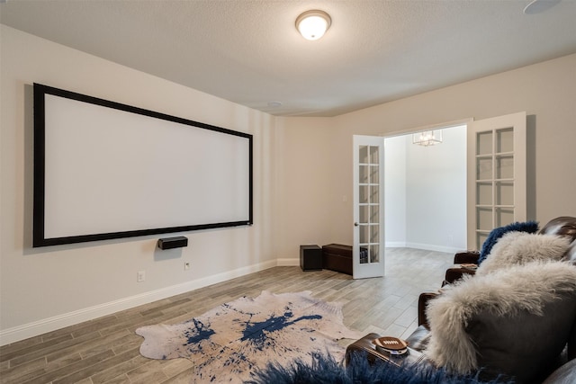 home theater with a textured ceiling, french doors, wood finished floors, and baseboards