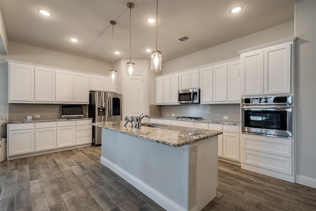 kitchen featuring a kitchen island with sink, dark wood-type flooring, white cabinetry, appliances with stainless steel finishes, and backsplash