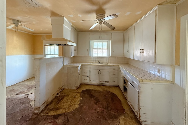 kitchen with tile countertops, premium range hood, ceiling fan, and a wealth of natural light