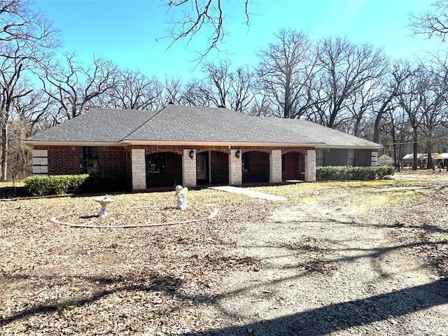 view of front of home with a shingled roof and brick siding