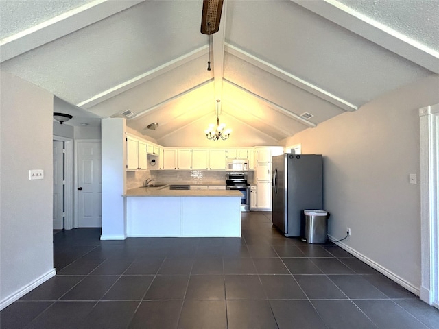 kitchen featuring decorative backsplash, dark tile patterned flooring, appliances with stainless steel finishes, a peninsula, and a notable chandelier