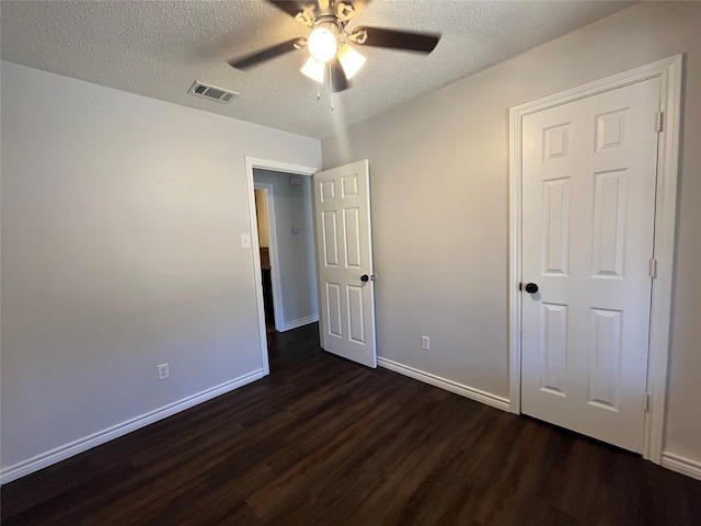 unfurnished bedroom with a textured ceiling, dark wood finished floors, visible vents, and baseboards