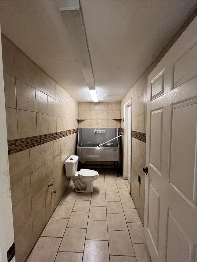 bathroom featuring toilet, tile patterned flooring, and tile walls