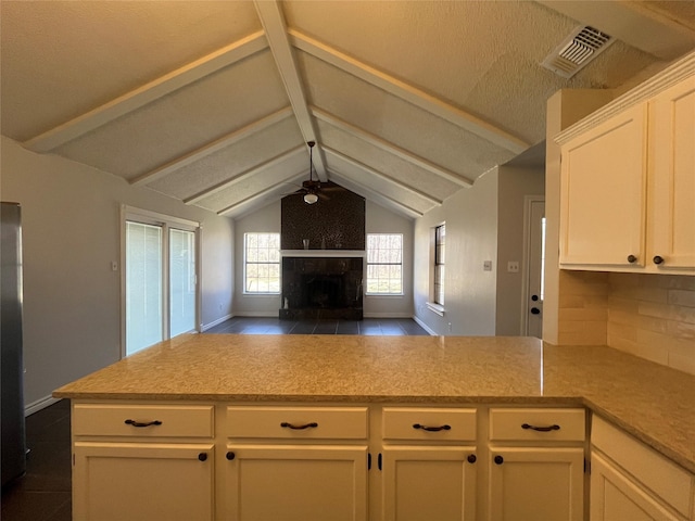 kitchen featuring ceiling fan, a fireplace with raised hearth, visible vents, white cabinets, and open floor plan