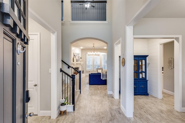 entryway with arched walkways, baseboards, an inviting chandelier, and stairs