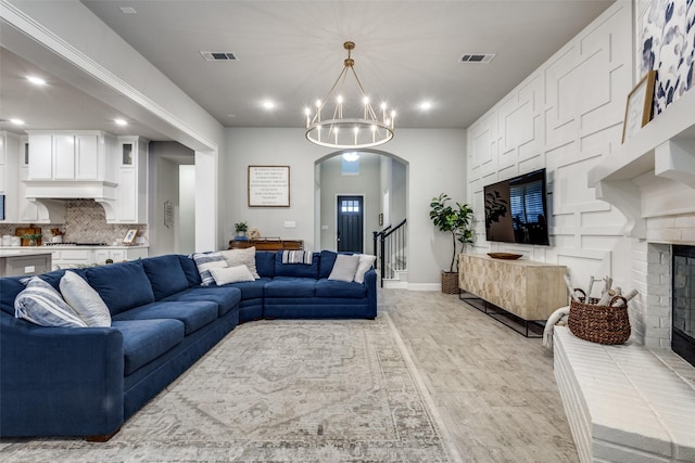 living area with visible vents, arched walkways, baseboards, a fireplace, and a chandelier