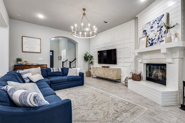 living room with visible vents, arched walkways, stairway, an inviting chandelier, and a fireplace