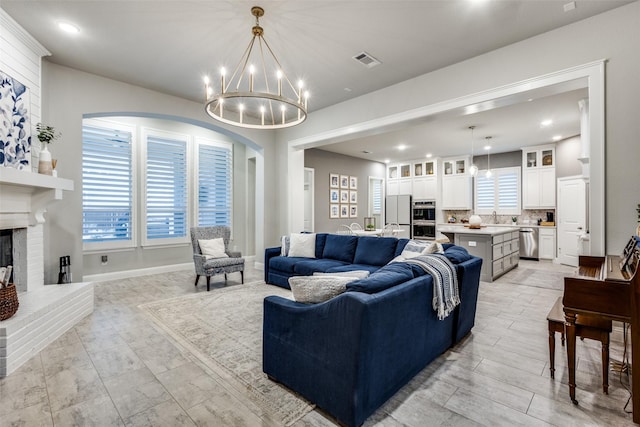 living room featuring a fireplace, a notable chandelier, recessed lighting, visible vents, and baseboards