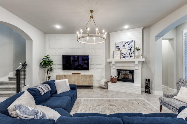 living room featuring baseboards, arched walkways, stairs, a fireplace, and recessed lighting