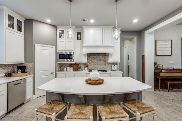 kitchen with stainless steel appliances, a breakfast bar, light countertops, and visible vents