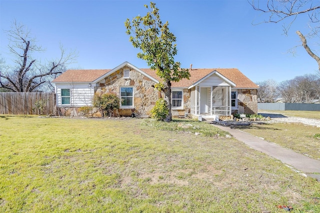 ranch-style home featuring stone siding, fence, and a front yard