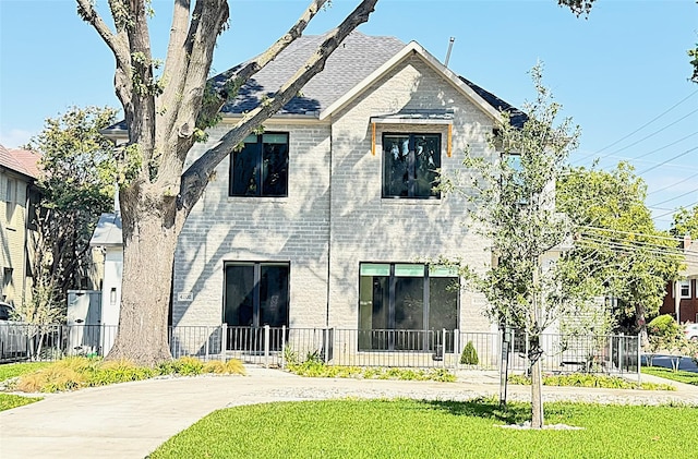 exterior space with a front lawn, fence, and brick siding