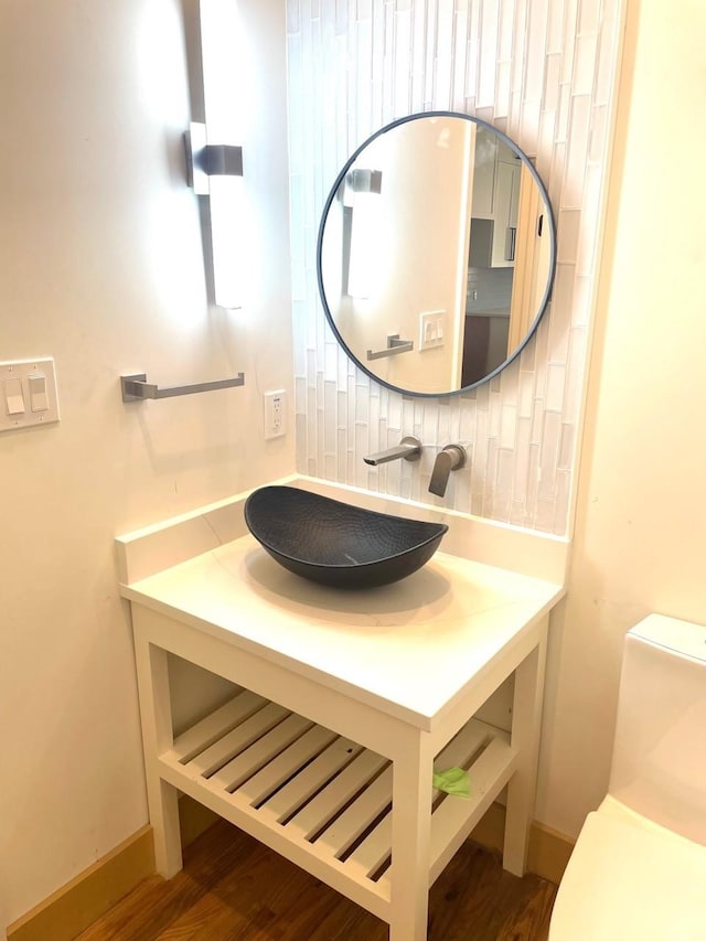 half bathroom featuring toilet, vanity, and decorative backsplash