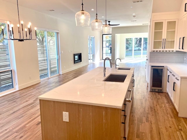 kitchen with beverage cooler, a center island with sink, decorative backsplash, open floor plan, and a sink