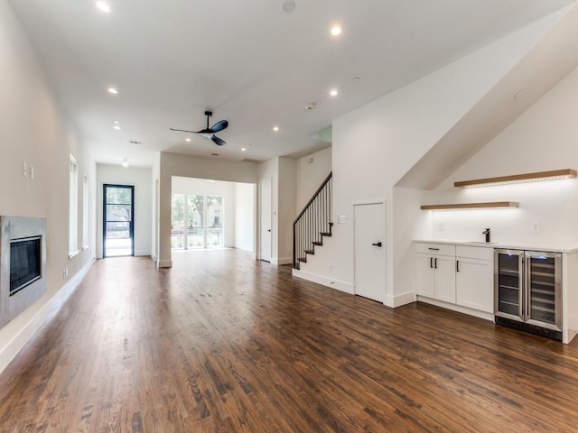 unfurnished living room with stairs, wine cooler, a premium fireplace, and dark wood finished floors