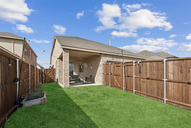 rear view of property with a patio, brick siding, a lawn, and a gate