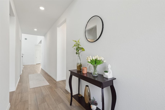 hallway with light wood-style floors, baseboards, and recessed lighting