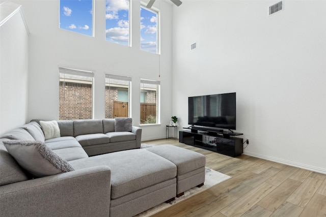 living room featuring light wood-type flooring, visible vents, and baseboards