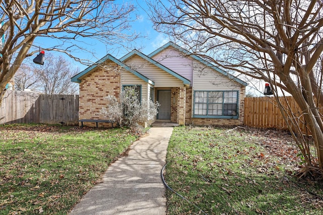 bungalow-style house featuring brick siding, a front yard, and fence