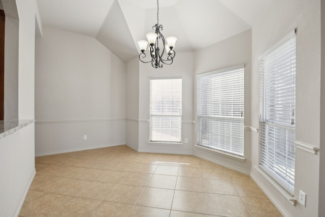 empty room with baseboards, vaulted ceiling, an inviting chandelier, and light tile patterned floors