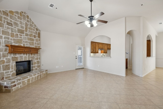 unfurnished living room with visible vents, baseboards, a ceiling fan, a fireplace, and high vaulted ceiling