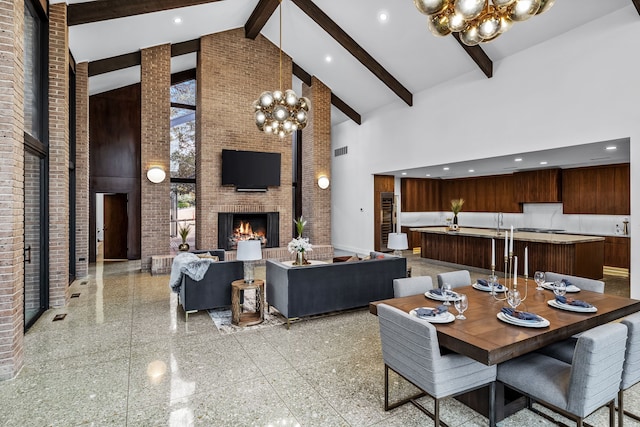 dining space with high vaulted ceiling, brick wall, granite finish floor, an outdoor brick fireplace, and an inviting chandelier