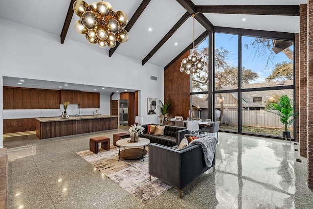 living room featuring a notable chandelier, visible vents, granite finish floor, high vaulted ceiling, and beamed ceiling