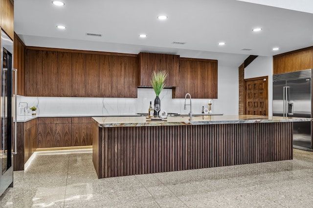 kitchen with built in fridge, recessed lighting, visible vents, granite finish floor, and modern cabinets