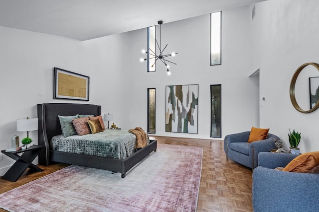 bedroom with visible vents, a notable chandelier, and a high ceiling