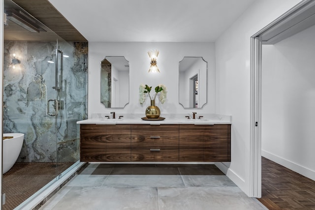 bathroom with a marble finish shower, double vanity, a freestanding bath, a sink, and baseboards