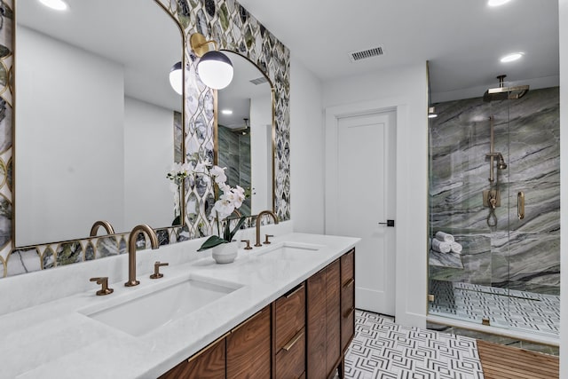 full bathroom featuring a marble finish shower, double vanity, a sink, and visible vents