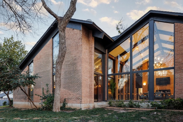 rear view of house featuring brick siding and a sunroom