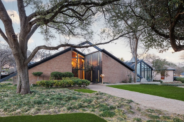 view of front of property featuring a front yard, brick siding, and driveway