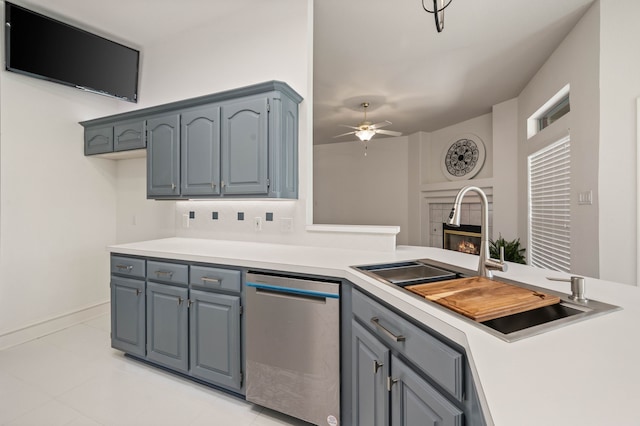 kitchen featuring a sink, dishwasher, a tiled fireplace, and light countertops