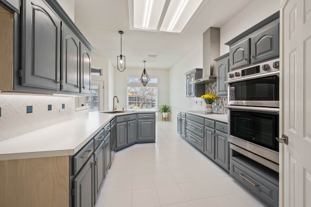 kitchen featuring backsplash, gray cabinets, double oven, and a sink