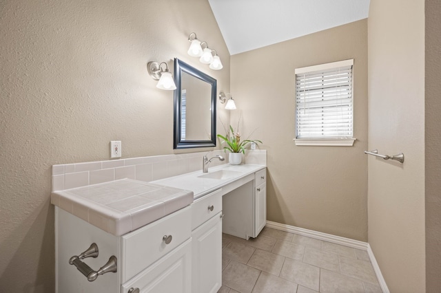 bathroom with vanity, tile patterned floors, baseboards, and lofted ceiling