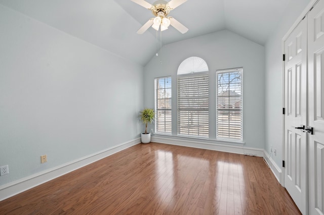 unfurnished room featuring baseboards, wood finished floors, a ceiling fan, and vaulted ceiling