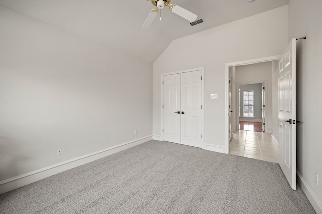 unfurnished bedroom featuring a ceiling fan, visible vents, vaulted ceiling, a closet, and light carpet