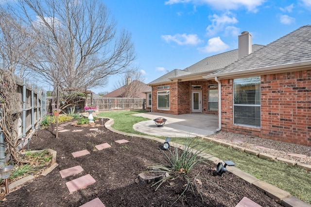 view of yard with a fire pit, a fenced backyard, and a patio area