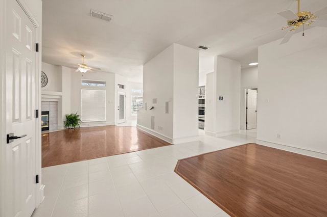 entrance foyer with wood finished floors, a fireplace, visible vents, and ceiling fan