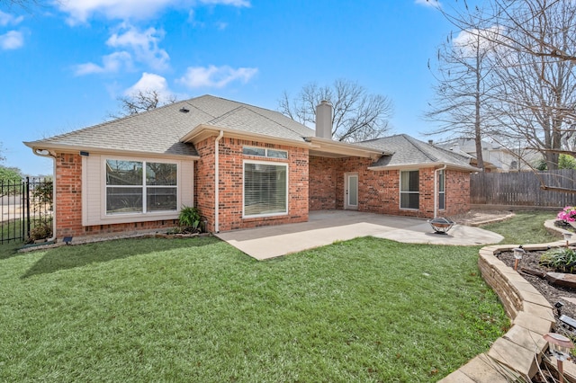 back of property with a lawn, a patio, fence, brick siding, and a chimney