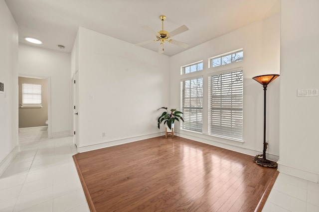 empty room featuring ceiling fan, baseboards, plenty of natural light, and wood finished floors