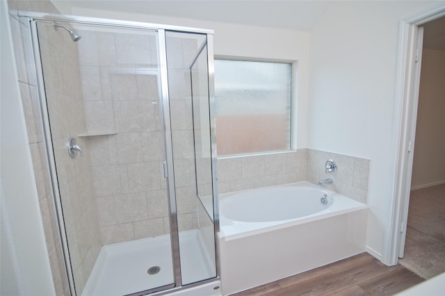 full bath featuring wood finished floors, a shower stall, and a bath