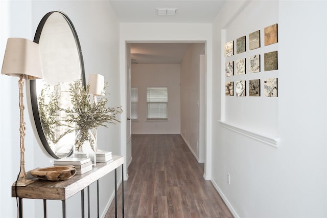 corridor with dark wood-type flooring, visible vents, and baseboards