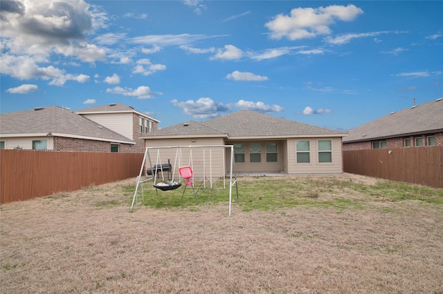 rear view of house with a fenced backyard and a yard