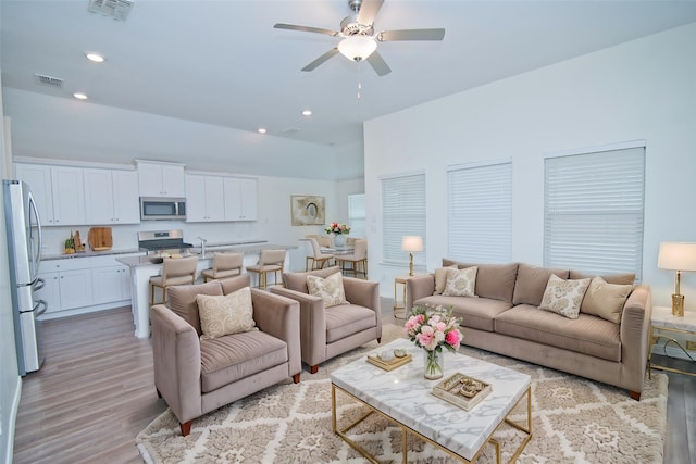 living area featuring light wood-style flooring, visible vents, a ceiling fan, and recessed lighting