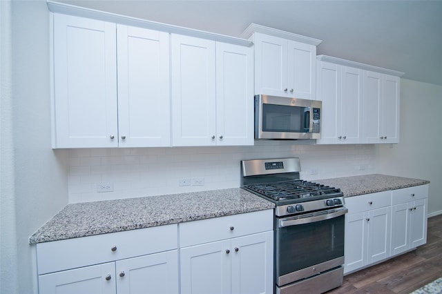 kitchen with tasteful backsplash, appliances with stainless steel finishes, white cabinets, and dark wood-type flooring