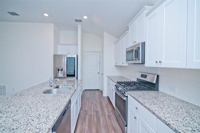 kitchen with appliances with stainless steel finishes, a sink, visible vents, and tasteful backsplash